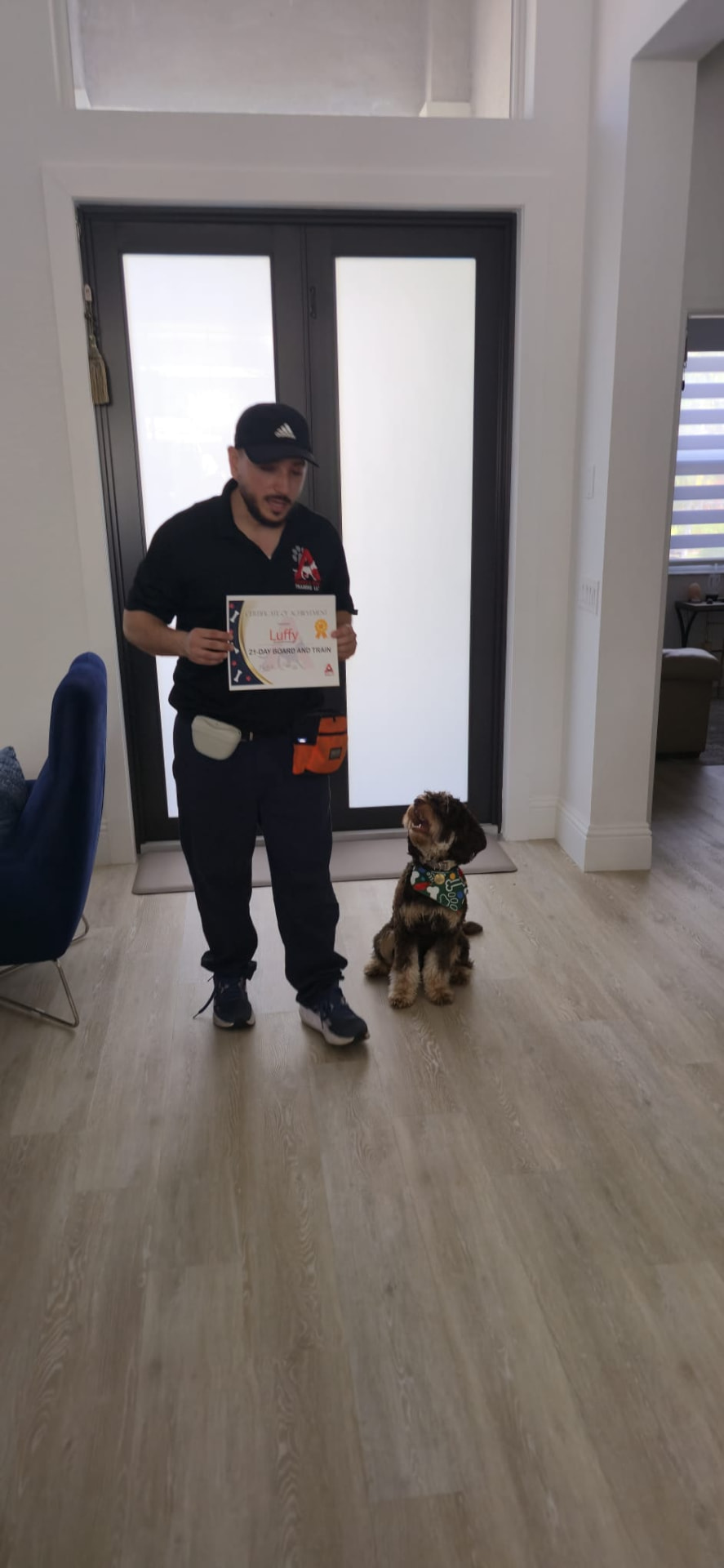 Trainer presenting Luffy's 21-Day Board and Train certificate with the dog sitting attentively.